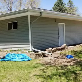 A single-story house with a white roof gutter system running along the roofline. Downspouts efficiently direct water away from the foundation, ensuring proper drainage and protecting the landscaping. The system is clean, functional, and well-installed.