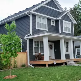 Dark siding contrasts with bright white gutters, highlighting the roof's clean lines. Seamless gutters protect the home from Minnesota weather.