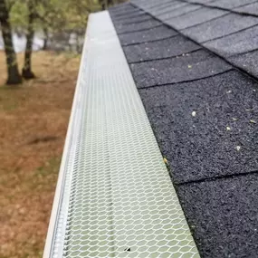 A roof gutter guard installed over the gutter system, designed to prevent leaves and debris from clogging while ensuring smooth water flow.