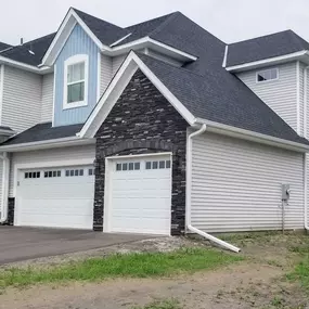 New home with clean white gutters & downspouts installed. Notice how they protect the siding & foundation from water damage, running along the roofline for efficient drainage.