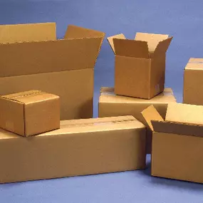 A collection of brown corrugated cardboard shipping boxes in various sizes, arranged against a solid blue background. Some boxes are open, while others are closed, showcasing their versatility for different packaging and shipping needs.