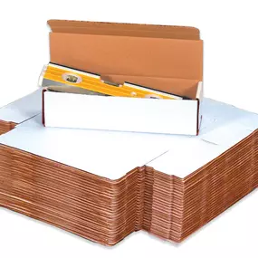 A stack of white corrugated literature mailers with one open box containing a yellow level tool, demonstrating their usage for securely packaging and shipping flat or narrow items. These durable mailers have a white exterior and a brown interior, providing a clean and professional appearance for mailing documents, books, or tools.