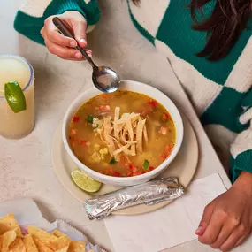 Tortilla Soup - Homemade chicken broth with roasted chicken, corn, green chiles, tomatoes & cilantro, topped with cheese, diced avocado & tortilla strips.