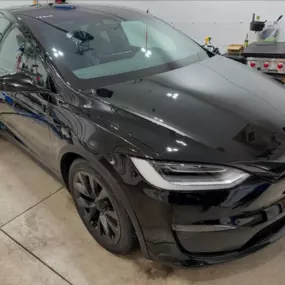 A black Tesla Model X freshly detailed with our premium exterior detailing and paint protection service, showing a high-gloss, mirror-like finish in a clean garage setting.