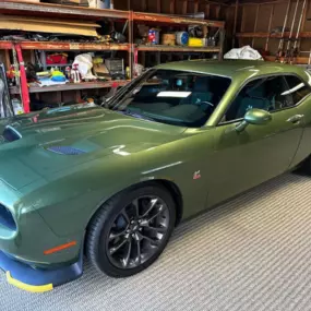This green Dodge Challenger stands out in the garage after a Showroom Shine exterior detailing, with a rich gloss that enhances the bold color and muscle car design.