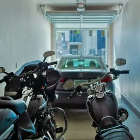 apartment garage showing two motorcycles in the foreground and Car
