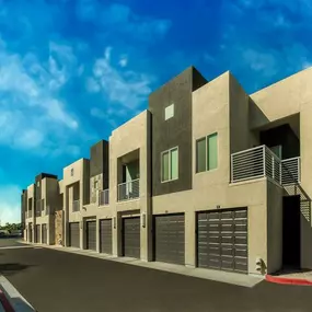 Exterior view of a building with beige and dark grey walls. There is a blue sky.
