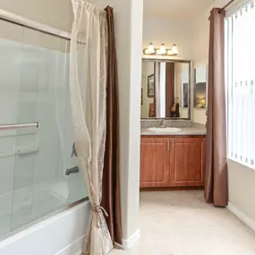 A bathroom with a bathtub and a view of a sink and window