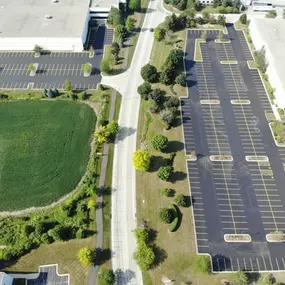 Aerial view of a freshly repaved and painted parking lot with trees and grass seen to the left.
