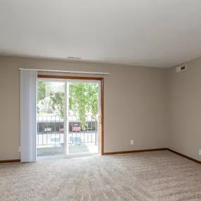 an empty living room with sliding glass doors to a patio
