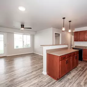 an empty kitchen and living room with wood floors and wooden cabinets