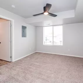 an empty living room with a ceiling fan and a window