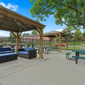 A park with a pavement, a gazebo, a bench and a table.