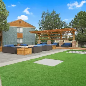 A large building with a wooden pergola and a green lawn in front.
