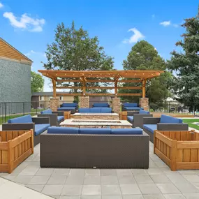 A wooden pergola is situated above a blue couch and a wooden table.