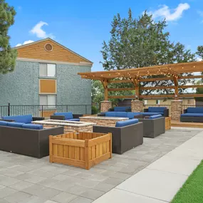 A patio with a wooden pergola and grey cushioned seating.