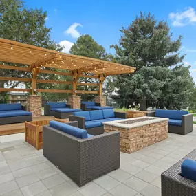 A patio with a wooden pergola and blue cushioned furniture.