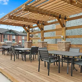 A wooden deck with a table and chairs under a pergola.