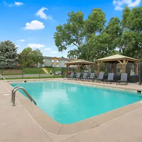 A swimming pool surrounded by a black fence and trees.