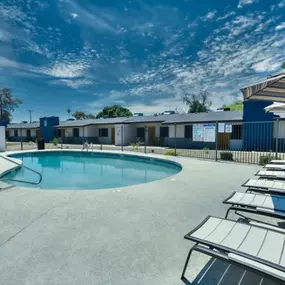 A swimming pool surrounded by sun loungers and umbrellas.