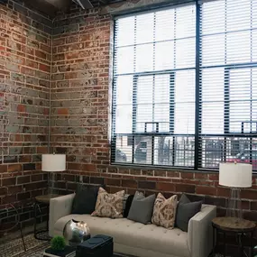 A living room with a couch, two chairs, and a table with a lamp on it