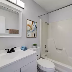 A white bathroom with a white toilet, sink, and bathtub