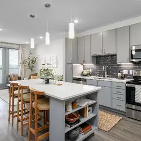 thoughtfully designed kitchen features contemporary gray cabinetry, stainless steel appliances, and a spacious island with bar seating
