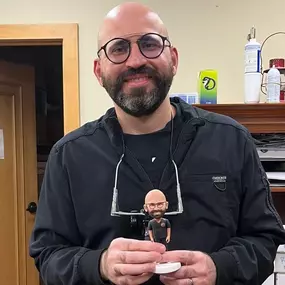 Dr. Zahir Kouzbari, Dental Depot's dentist in Midwest City, holds a bobblehead of himself.