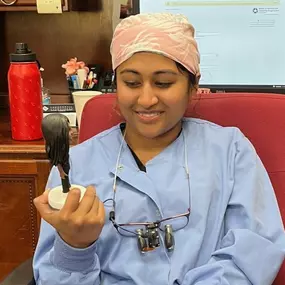 Dr. Ashnu Raju, Dental Depot's dentist in Midwest City, holds a bobblehead of herself.