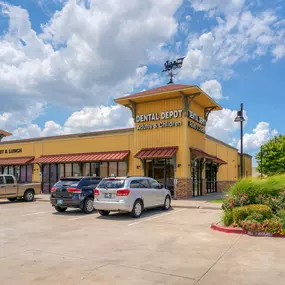 Exterior view of Dental Depot's Moore dental clinic with yellow walls and a red roof.