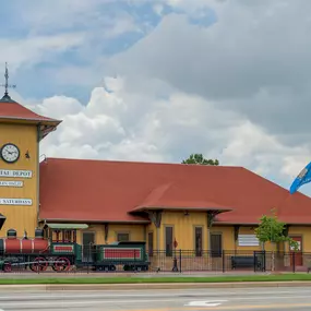 Exterior view of Dental Depot's Norman dentist office with a clock tower, model train, and yellow walls.
