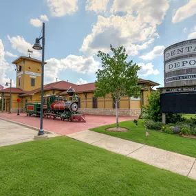 Exterior view of Dental Depot's Oklahoma City Dental Clinic on W. Hefner Rd with a model train, flagpole, water tower, and a yellow exterior.