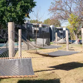 a playground with hammocks and a fence and houses in the background