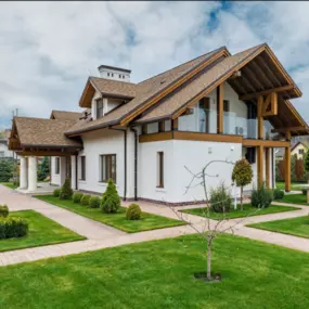 Modern European-Style Custom Home with Premium Exterior Finishes

This stunning two-story custom home blends modern European design with warm natural finishes. Featuring a white stucco exterior, rich wood trim, and a steeply pitched roof with architectural shingles, the home makes a bold statement in craftsmanship and curb appeal. A covered entryway with classic columns adds elegance, while large windows and a glass-paneled balcony offer contemporary touches. Manicured landscaping and intersecti