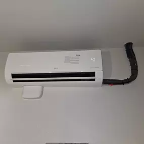 An installed LG wall-mounted mini-split indoor unit set to 64°F, part of a ductless HVAC system serviced by Perry Mechanical Inc.