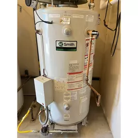 A commercial-grade A.O. Smith water heater unit with various copper and gas line connections, maintained or installed by Perry Mechanical Inc.