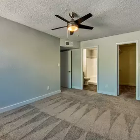 A room with a ceiling fan and carpeted floor.