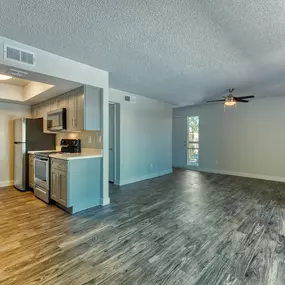 A spacious kitchen with wood flooring and a ceiling fan.