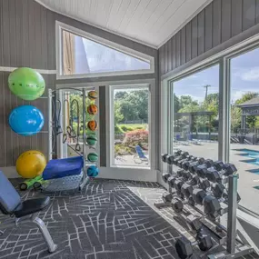 The gym with a view of a swimming pool and glass doors