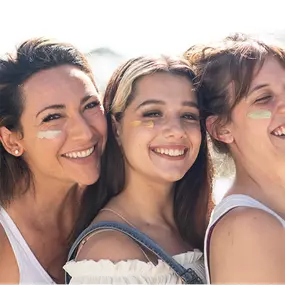 Three happy women wearing organic skincare cream outdoors, enjoying natural beauty and self-care under the sun.