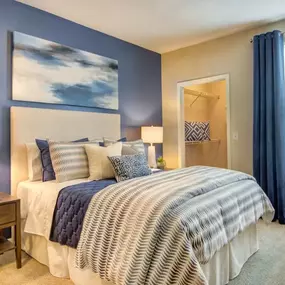 A stylish bedroom at Grande Club Apartments with a blue accent wall and elegant décor.