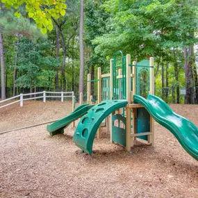 A vibrant playground at Grande Club Apartments surrounded by lush greenery.