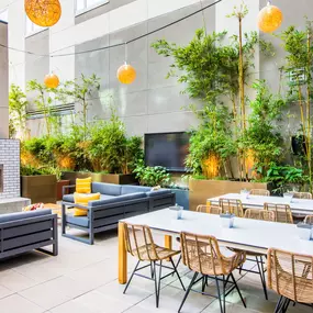 A modern outdoor dining area with a fireplace and seating for multiple people.