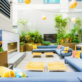A modern outdoor seating area with blue couches and yellow cushions.