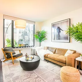A living room with a brown couch, a coffee table, and a large window.