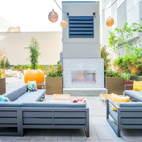 A grey sofa with blue cushions is on a patio.