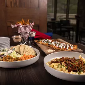 A delicious spread of hearty dishes including scrambled eggs, a savory pasta bowl, and french fries, perfect for sharing at a casual meal.