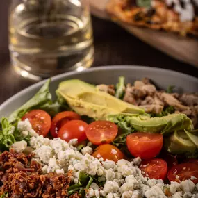 a colorful Cobb salad with a drink and flatbread on the side.