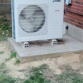 A York outdoor HVAC unit is installed on a concrete slab, ensuring efficient heating and cooling for residential climate control.