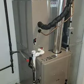 A modern furnace unit installed in a utility room, featuring insulated piping, ventilation, and essential plumbing connections for efficient heating.